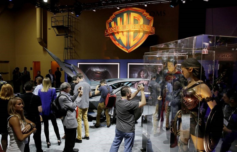 Crowds taking pictures of Batman, Superman, and Wonder Woman's costumes